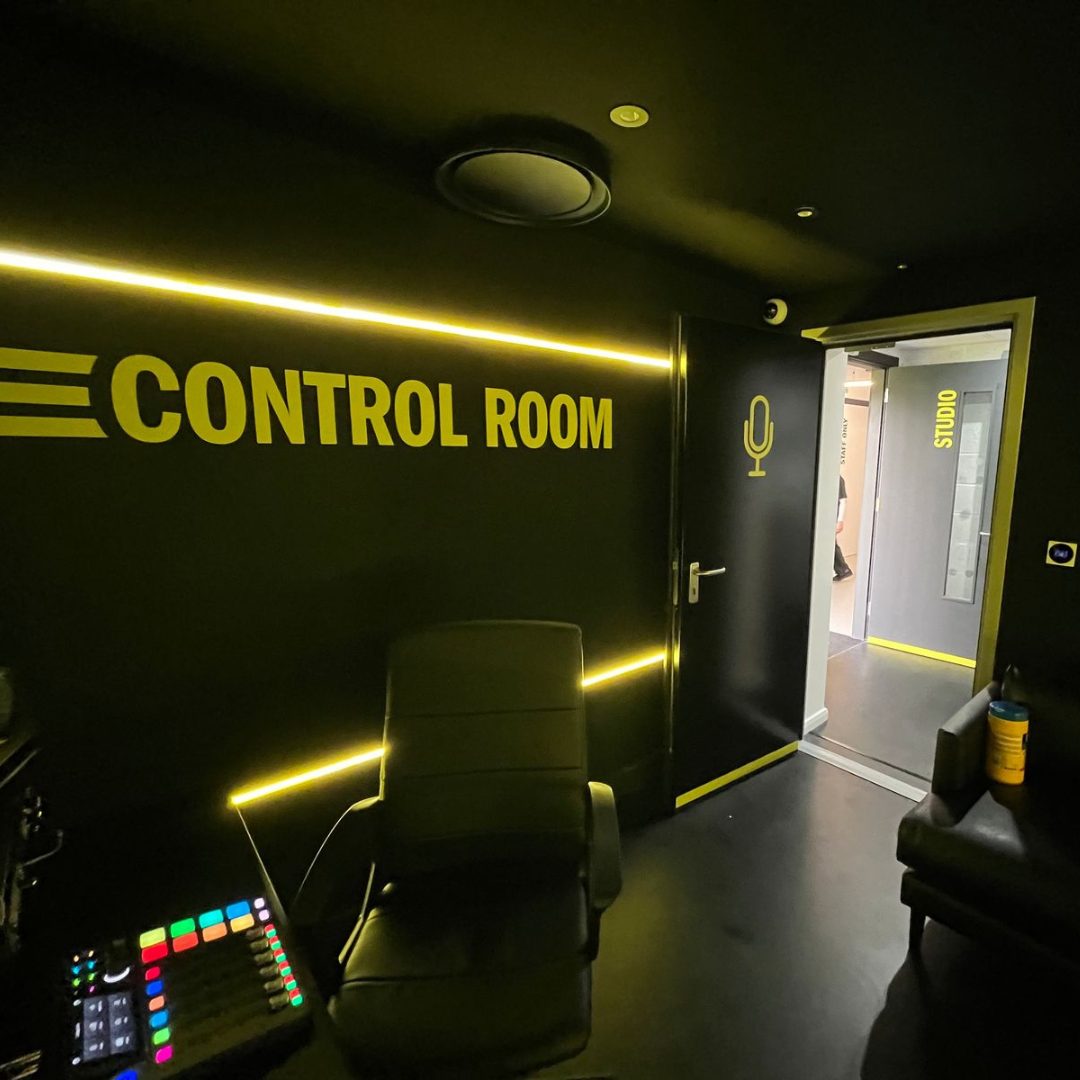 Podcast studio with a wall printed with huge yellow text saying "CONTROL ROOM"