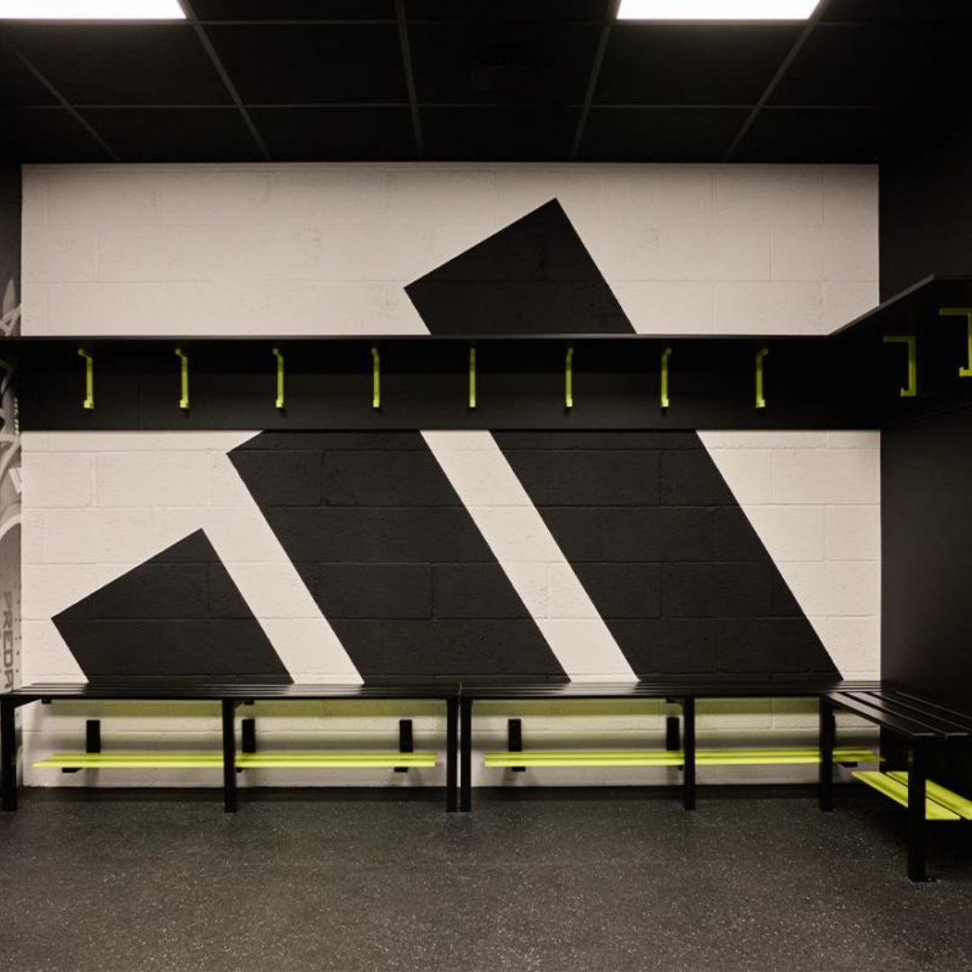 Sports changing rooms with a huge adidas logo in the middle of a wall